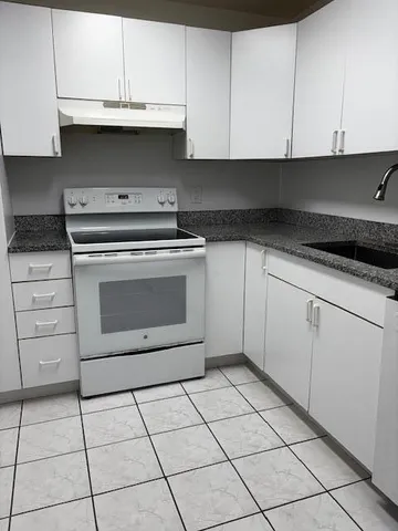 a kitchen with white cabinets and appliances