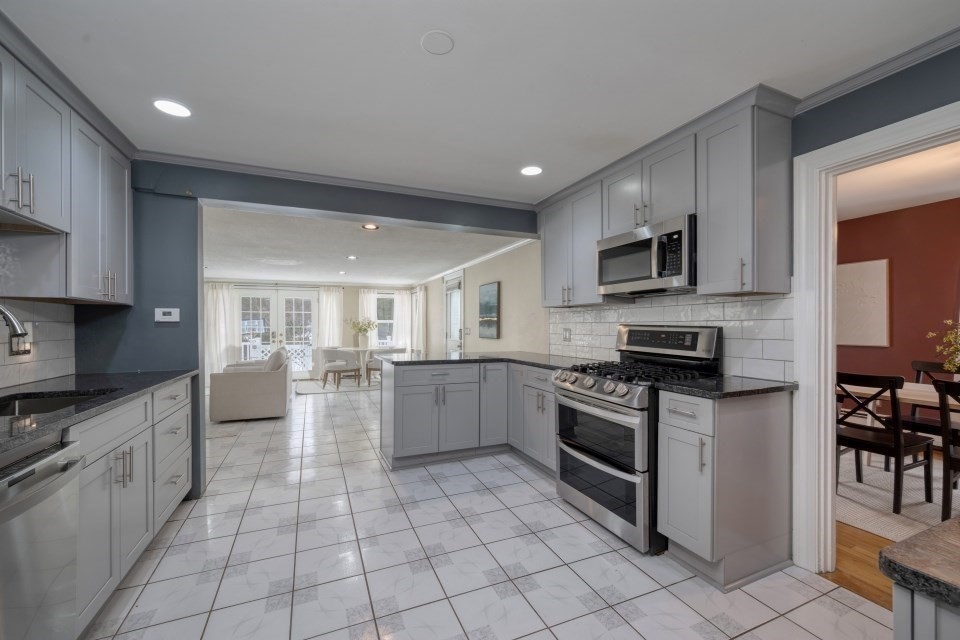 193 Vincent Road Dedham, MA 02026 - Photo 13 of 42 a kitchen with stainless steel appliances granite countertop a stove top oven a sink dishwasher a dining table and chairs with wooden floor