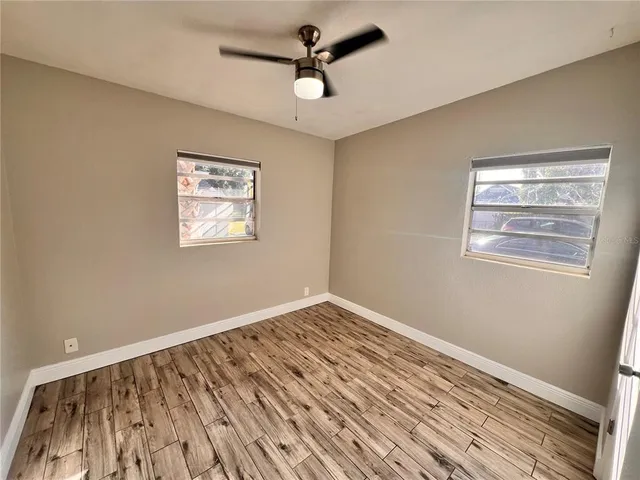 a view of empty room with wooden floor and ceiling fan