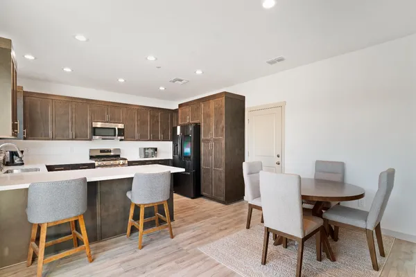 a kitchen with a dining table chairs and refrigerator