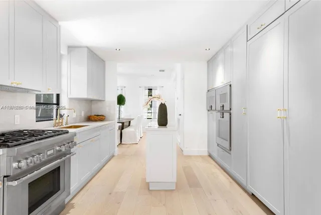a large white kitchen with a refrigerator a stove a sink and white cabinets