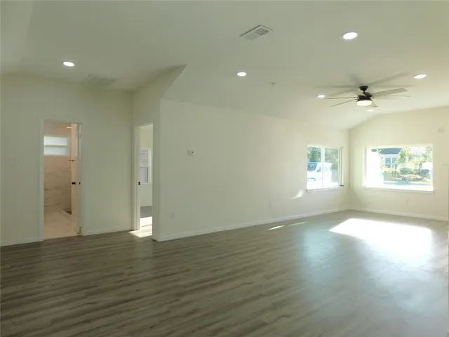 an empty room with wooden floor and windows