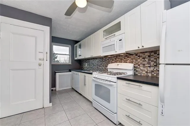 a kitchen with granite countertop white cabinets and white appliances