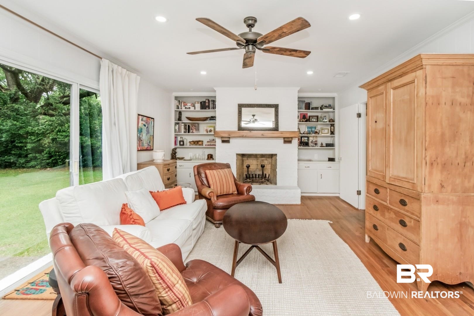 4596 Hawthorne Place Mobile, AL 36608 - Photo 24 of 34 Living area featuring hardwood flooring, a fireplace with a wood mantle, built-in shelving, a ceiling fan, and sliding glass doors to the exterior
