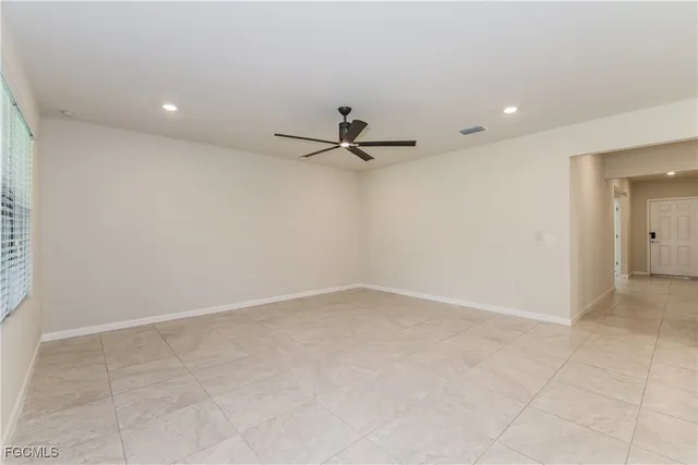 an empty room with a ceiling fan and carpet