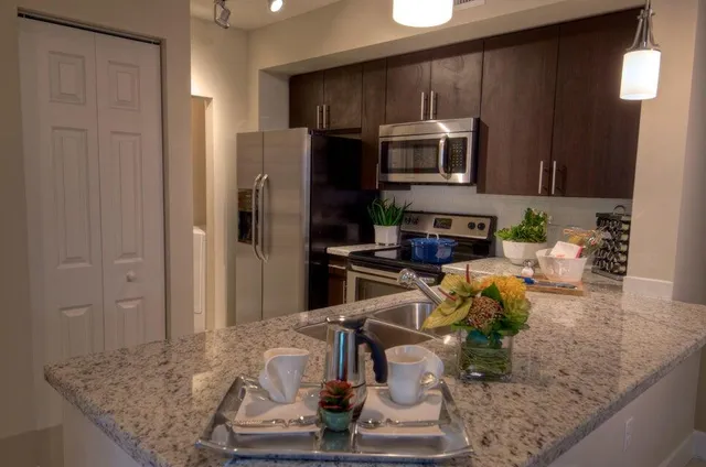 a kitchen with stainless steel appliances granite countertop a sink refrigerator and microwave