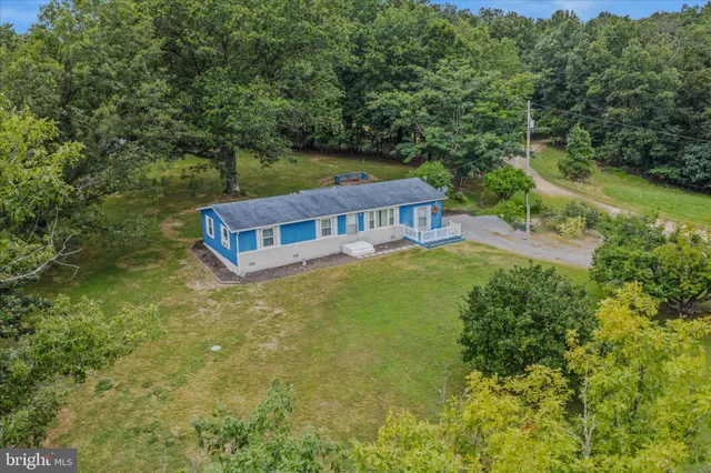 an aerial view of residential house with outdoor space and trees all around