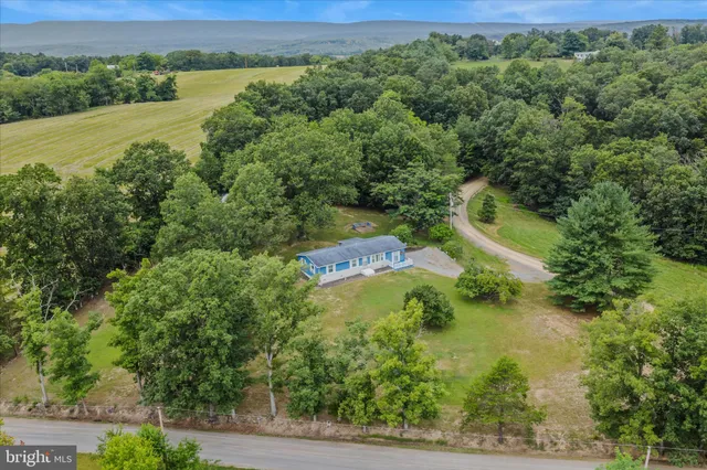 an aerial view of residential house with outdoor space and trees all around