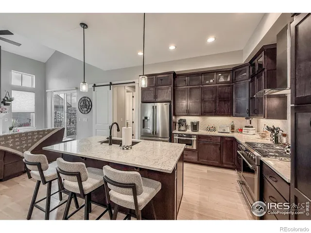 a kitchen with stainless steel appliances kitchen island granite countertop a stove a sink a refrigerator and chairs