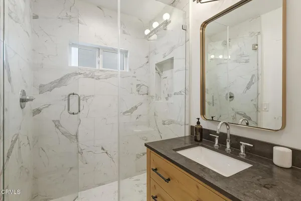 a bathroom with a granite countertop sink a mirror and shower