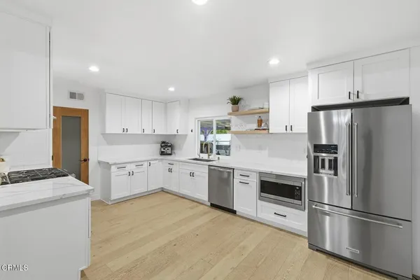 a kitchen with stainless steel appliances a refrigerator sink and white cabinets