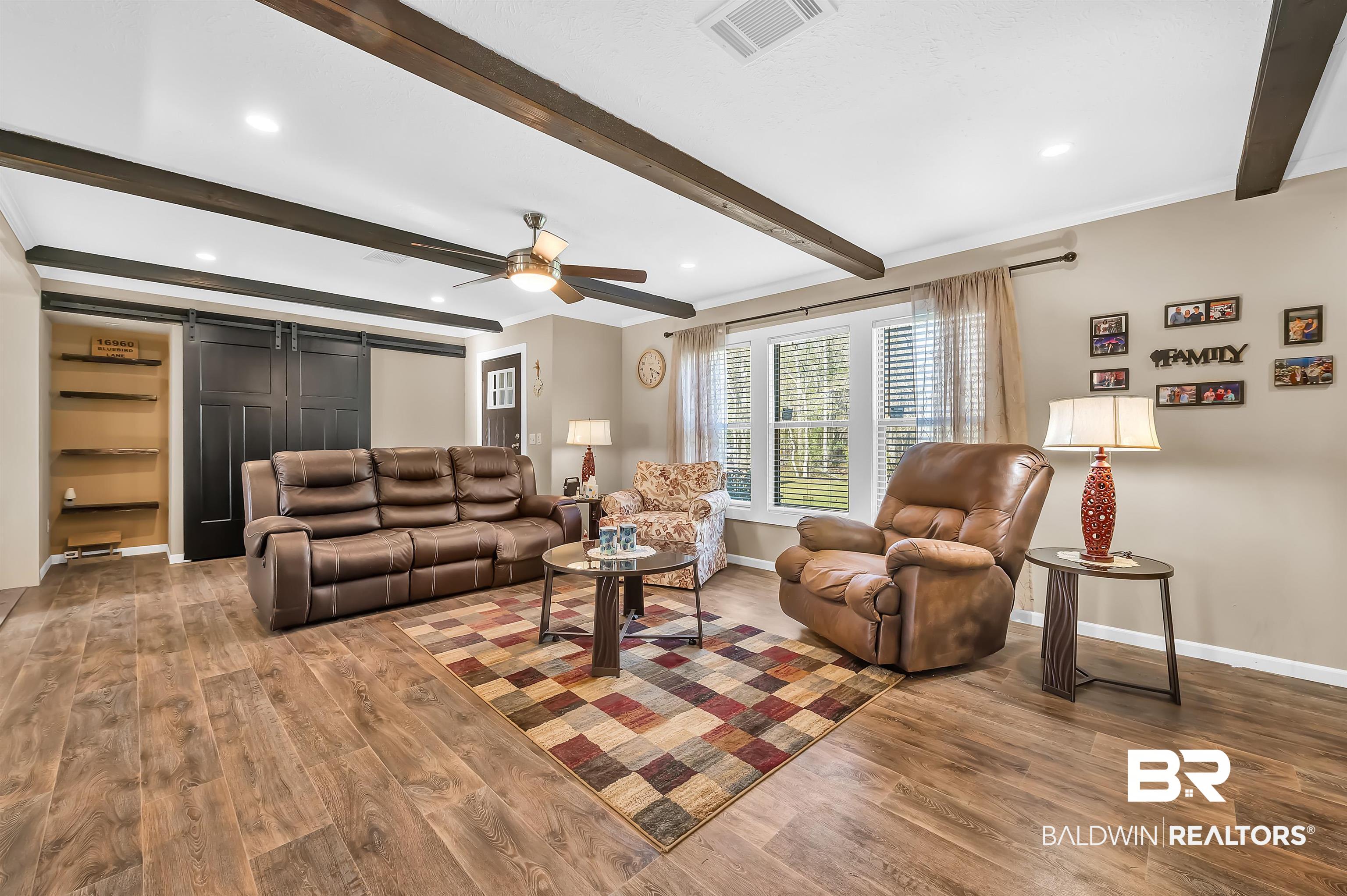 23233 Forland Road Silverhill, AL 36576 - Photo 11 of 33 Living room featuring visible vents, a barn door, wood finished floors, and beam ceiling
