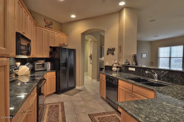 a kitchen with stainless steel appliances granite countertop a sink and a refrigerator