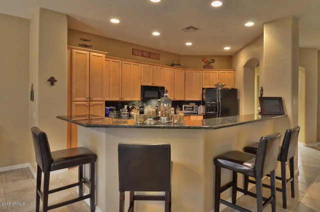 a kitchen with stainless steel appliances granite countertop white cabinets a sink and chairs