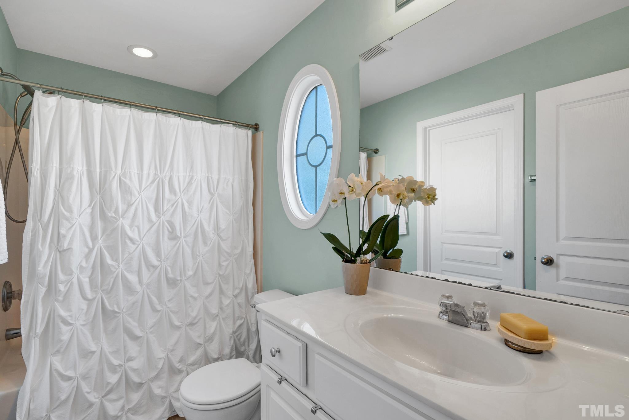 7618 Winners Edge Street Raleigh, NC 27617 - Photo 15 of 22 a bathroom with a sink a toilet and shower curtain