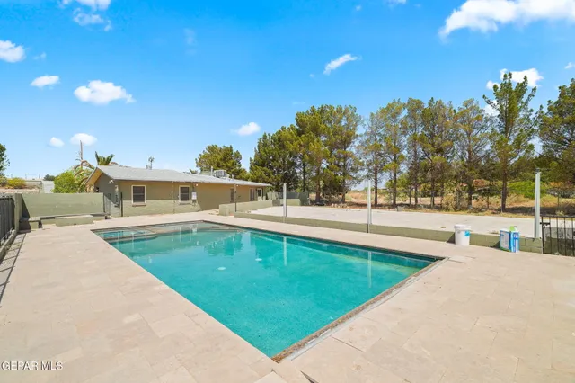 a view of swimming pool with outdoor seating and trees in the background