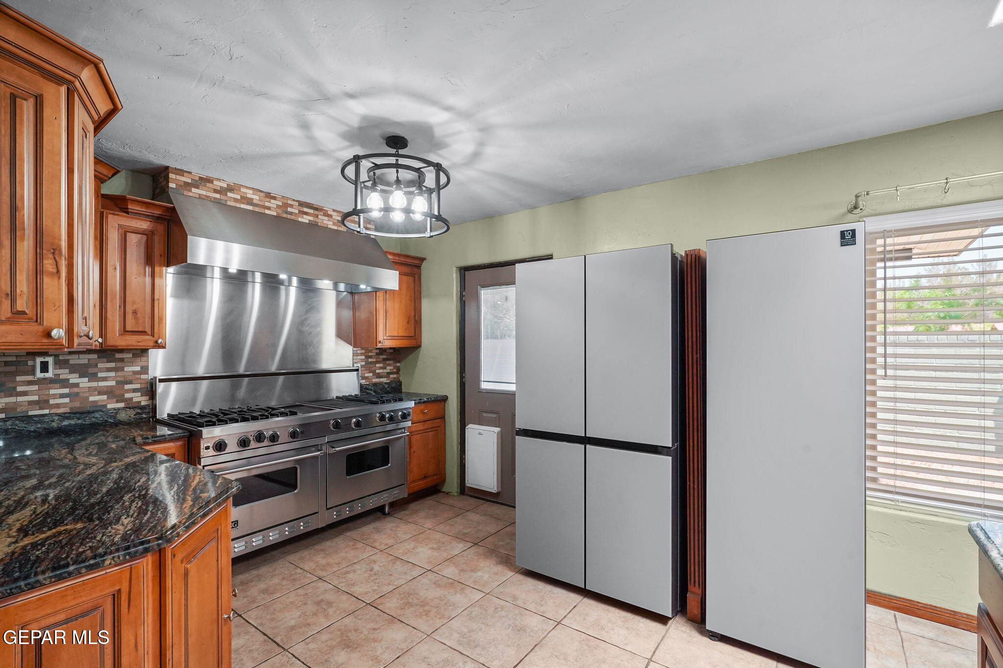 5300 Crawford Road Santa Teresa, NM 88008 - Photo 48 of 87 a kitchen with stainless steel appliances granite countertop a refrigerator a stove and a sink with wooden floor