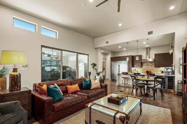 a kitchen with stainless steel appliances kitchen island granite countertop a dining table chairs and a refrigerator