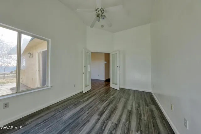 an empty room with wooden floor and a ceiling fan