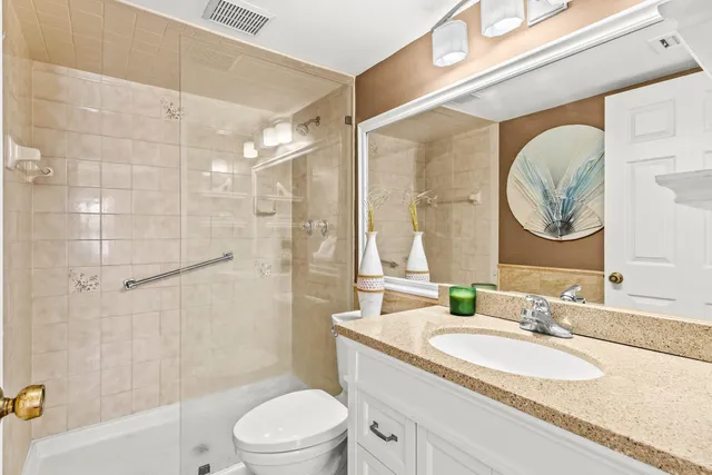 a bathroom with a granite countertop sink a toilet and shower