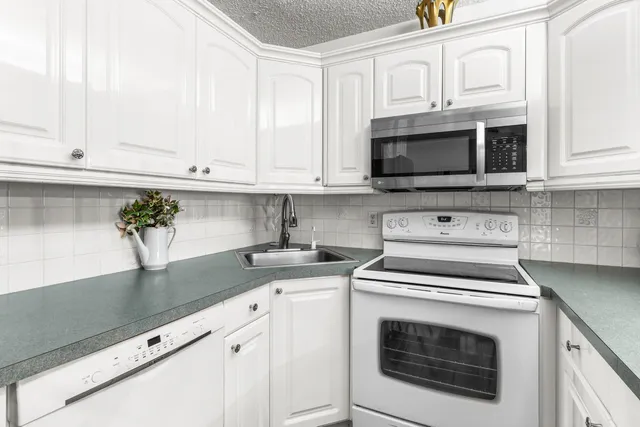 a kitchen with granite countertop white cabinets stainless steel appliances and a sink