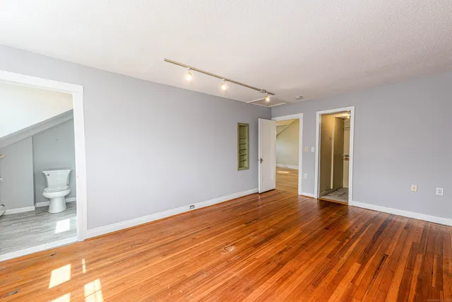 a view of an empty room with wooden floor and a window