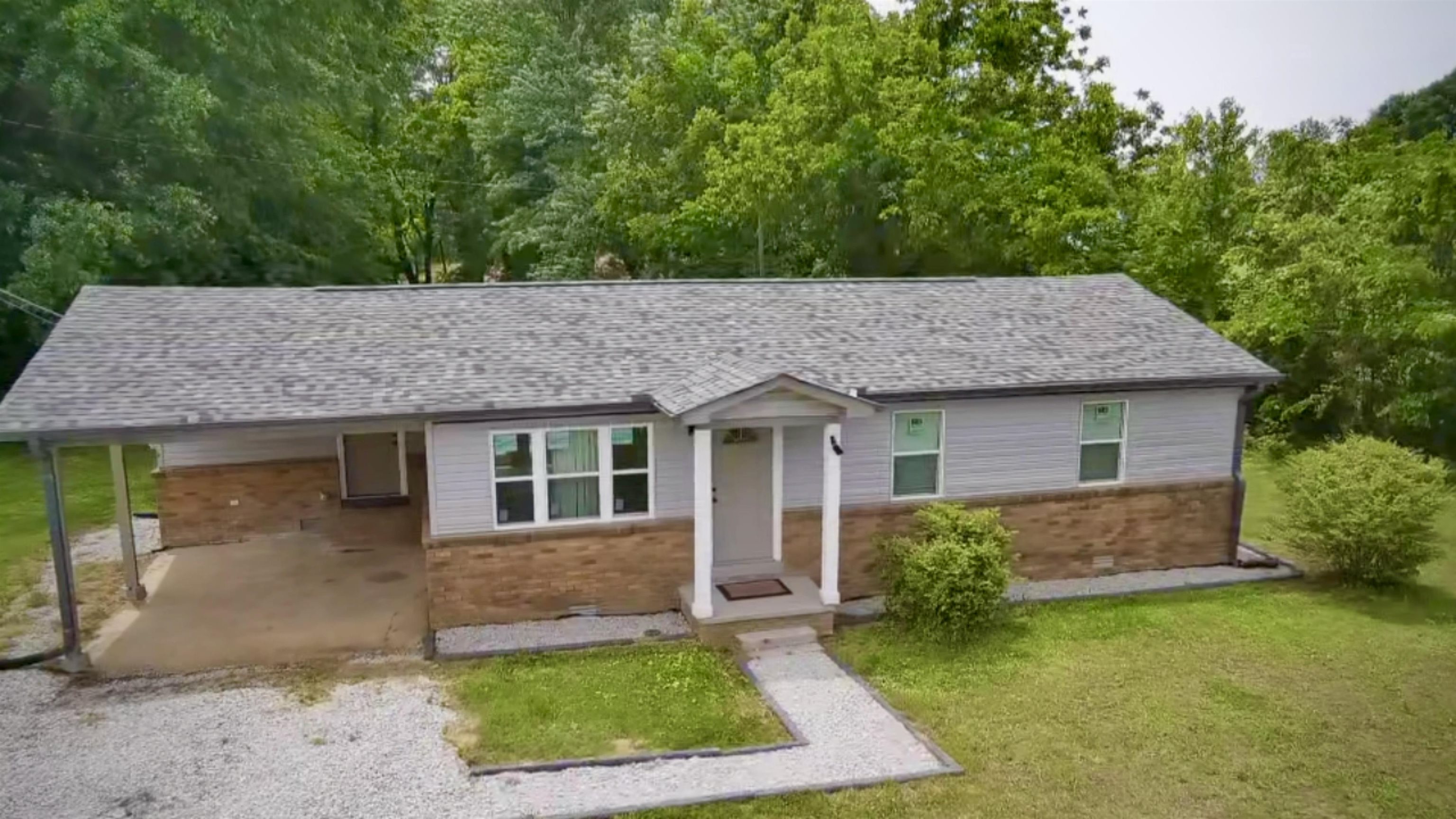 Ranch-style exterior featuring gray siding with a stone-finish foundation
