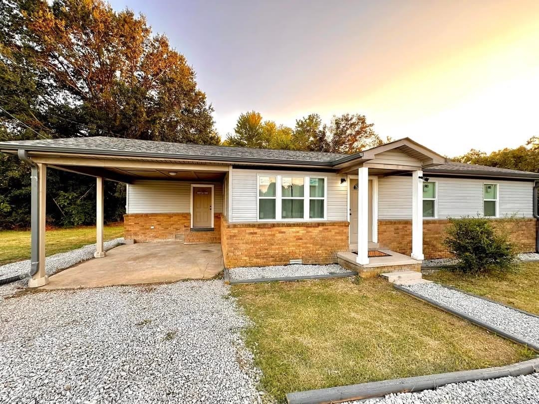 Ranch-style home featuring brick siding, a carport, a front yard, and driveway