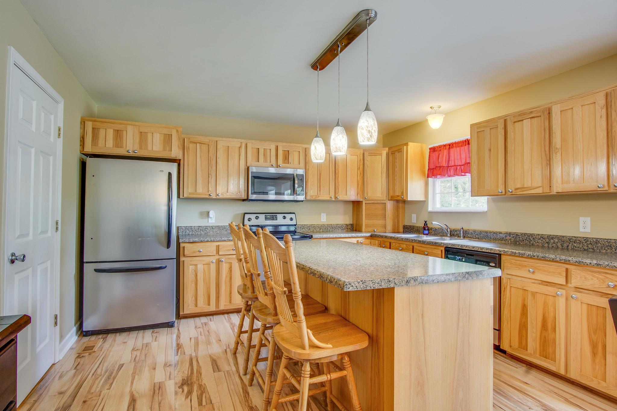 1674 Eno Road Dickson, TN 37055 - Photo 11 of 28 a kitchen with stainless steel appliances granite countertop a refrigerator a sink dishwasher a stove and white countertops with wooden floor