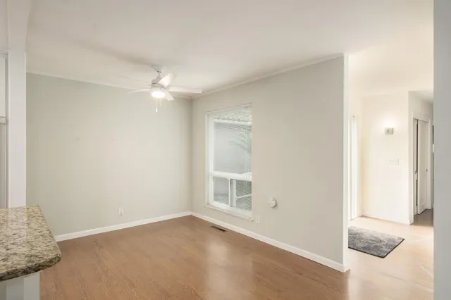 a view of an empty room with chandelier fan and fire place