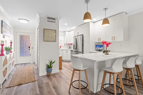a kitchen with stainless steel appliances a dining table chairs and refrigerator