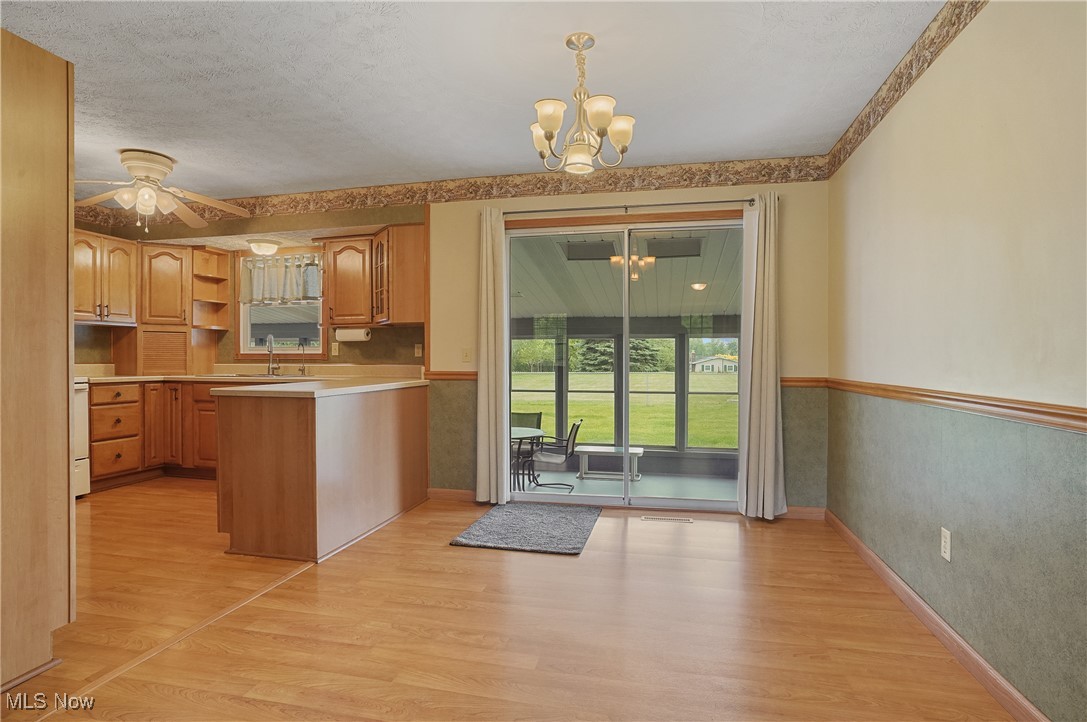 3262 Wright Road Northwest Uniontown, OH 44685 - Photo 13 of 37 Kitchen with a chandelier, a peninsula, light wood-style flooring, a ceiling fan, and light countertops