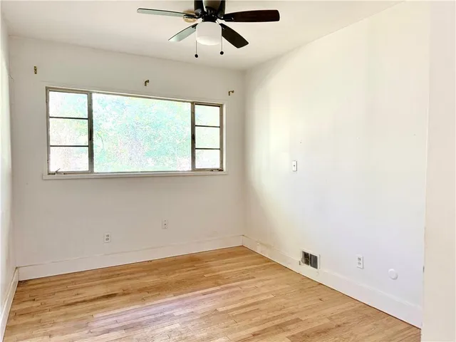 an empty room with a window and a ceiling fan