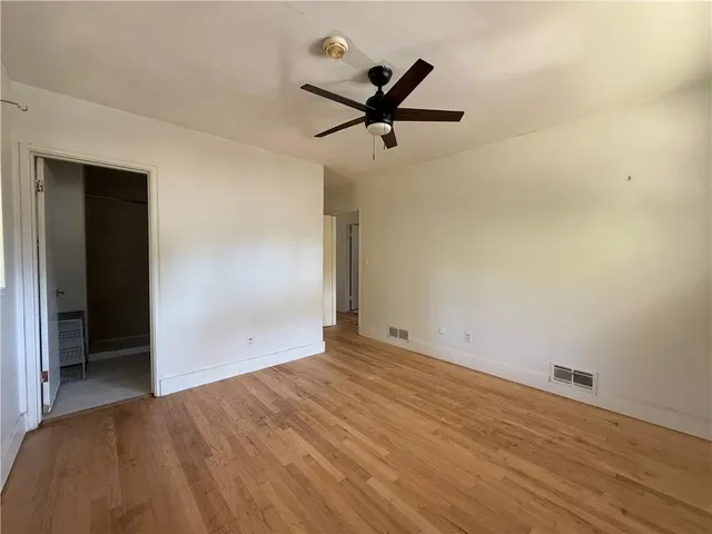 a view of a big room with wooden floor and a ceiling fan