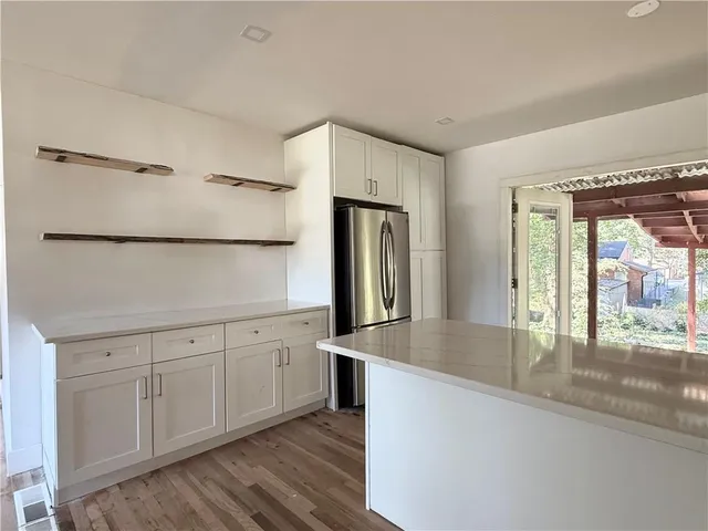a kitchen with stainless steel appliances granite countertop a refrigerator and a sink with wooden floors