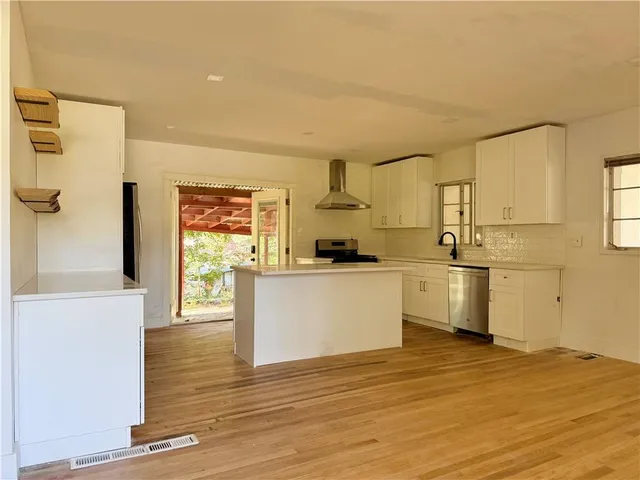 a kitchen with white cabinets and wooden floor