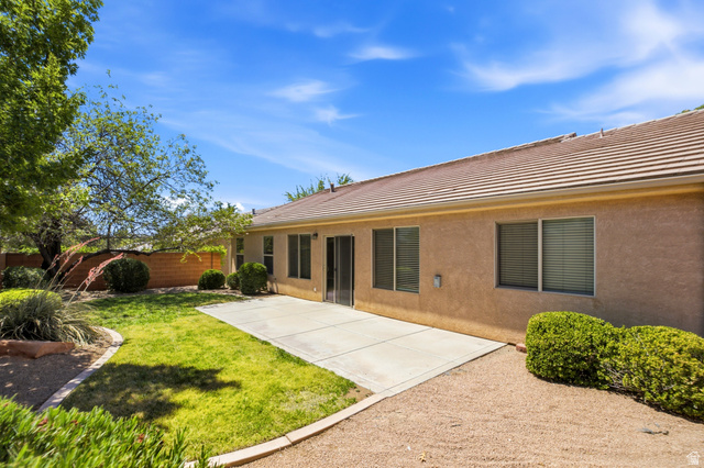 1630 East 2450th Street South, Unit 263 St. George, UT 84790 - Photo 21 of 24 Expansive backyard featuring a concrete patio, a combination of green lawn and gravel landscaping, and mature trees providing natural shade
