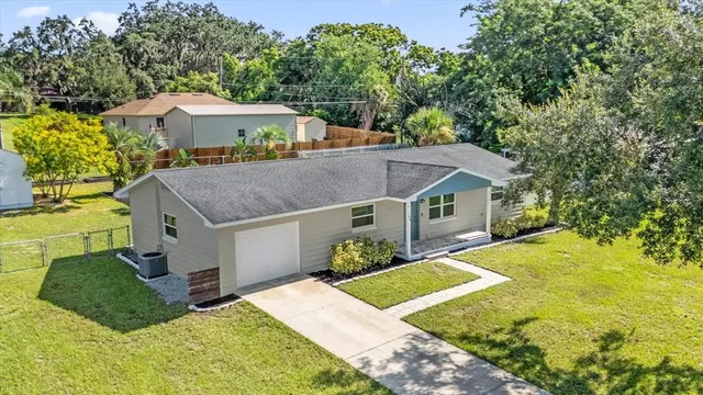 a aerial view of a house next to a yard with big trees