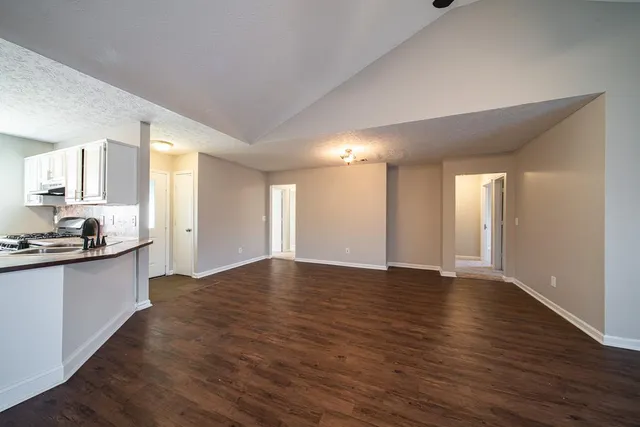 a view of an empty room with window and wooden floor