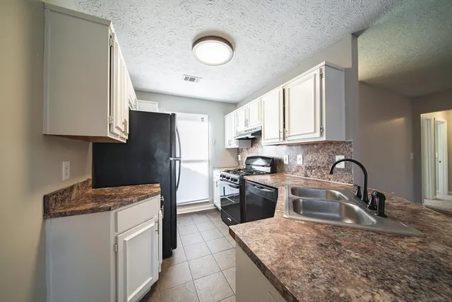 a kitchen with granite countertop a sink stainless steel appliances and white cabinets