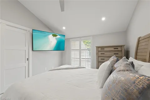 a bedroom with a large bed and a flat tv screen on dresser