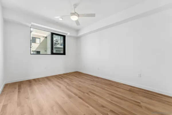 an empty room with wooden floor chandelier fan and windows