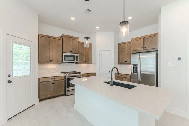 a kitchen with stainless steel appliances granite countertop a sink a stove a refrigerator and island with wooden floor