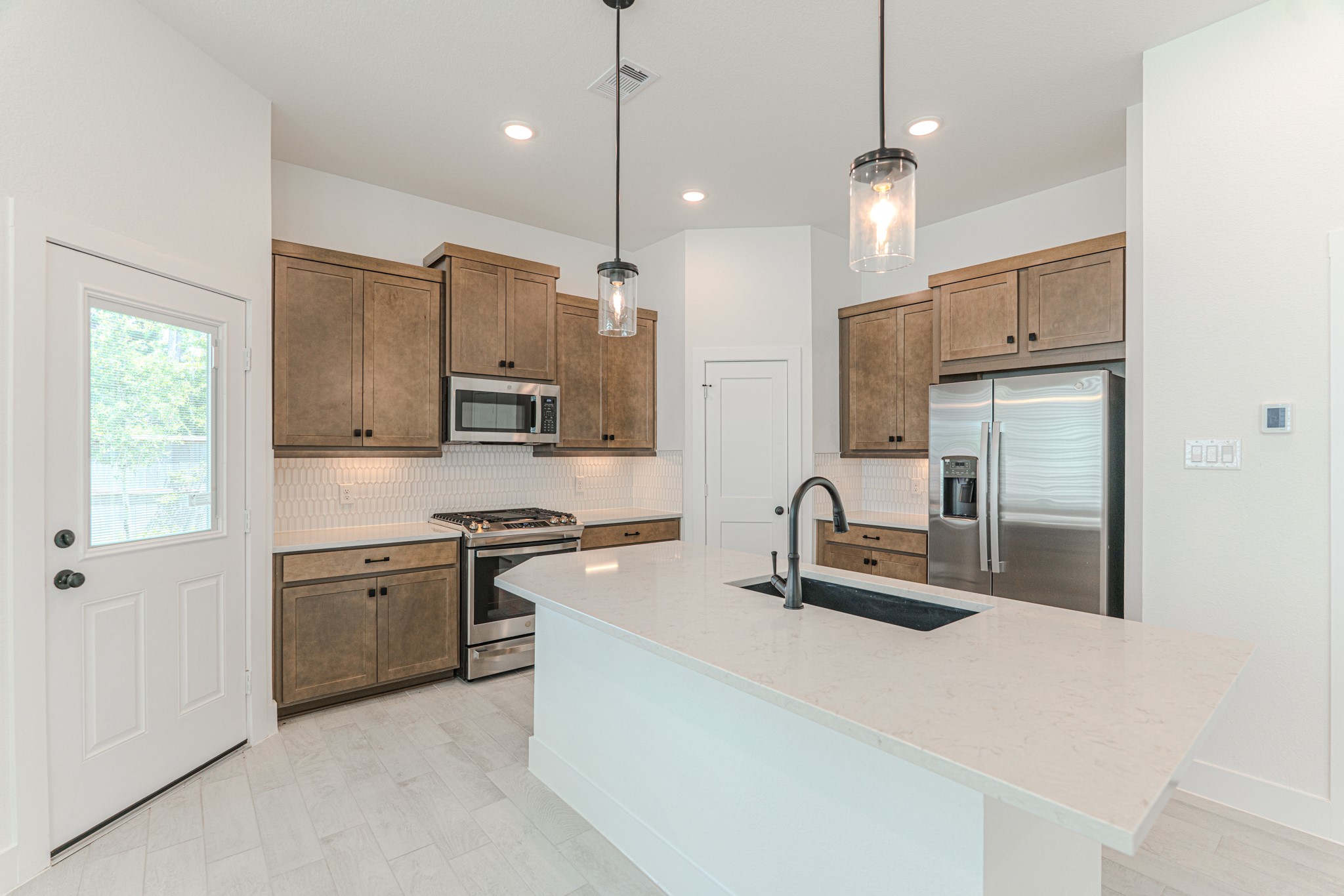 152 Red Cascade Trail Willis, TX 77318 - Photo 17 of 39 a kitchen with stainless steel appliances granite countertop a sink a stove a refrigerator and island with wooden floor