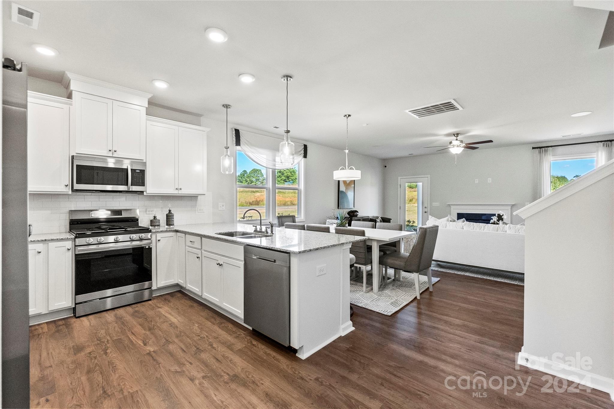 3182 Laurel Brook Drive Denver, NC 28037 - Photo 9 of 35 a kitchen with stainless steel appliances granite countertop a stove top oven a sink dishwasher a dining table and chairs with wooden floor