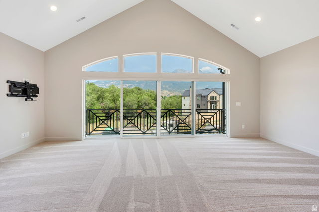 250 South Main Street, Unit 10 Alpine, UT 84004 - Photo 18 of 29 Spacious room featuring vaulted ceilings, a large sliding glass door, arched transom windows, recessed lighting, and a private balcony with decorative iron railings