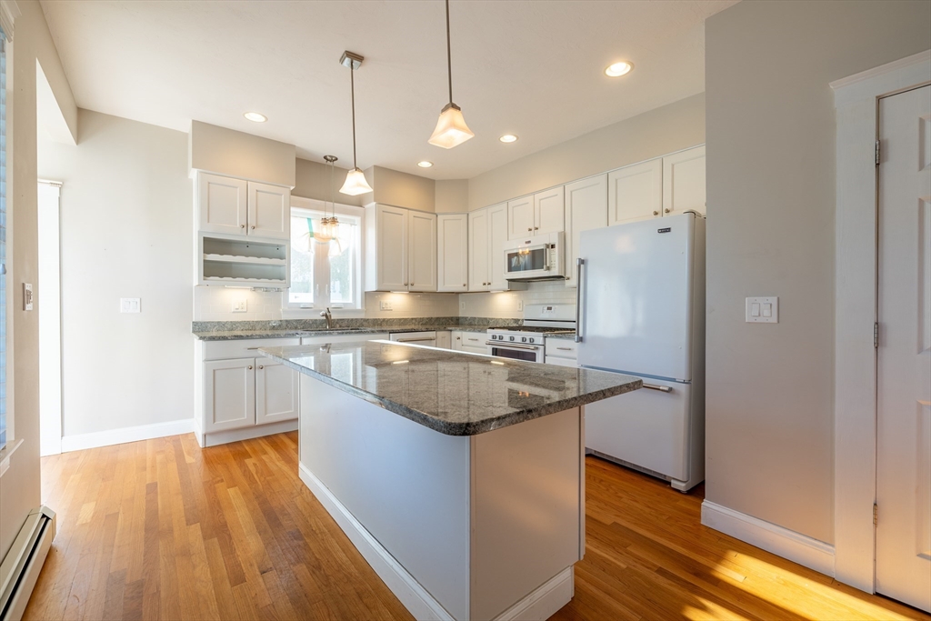 151 R Methuen Street, Unit 151R Lowell, MA 01850 - Photo 4 of 15 a kitchen with stainless steel appliances granite countertop a refrigerator a sink dishwasher a stove and white countertops with wooden floor