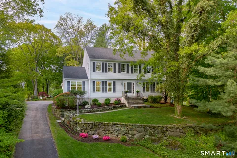 a front view of a house with a garden and trees