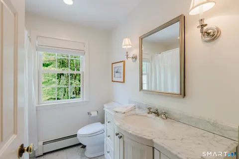 a bathroom with a granite countertop toilet a sink and a mirror