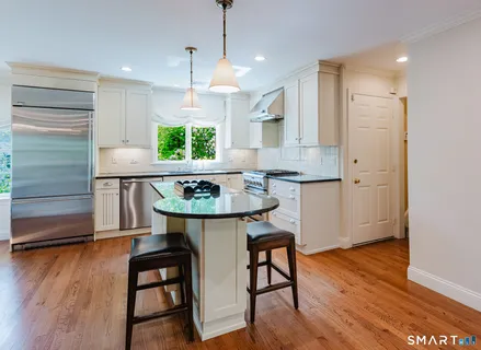 a kitchen with stainless steel appliances granite countertop a white table chairs and a window